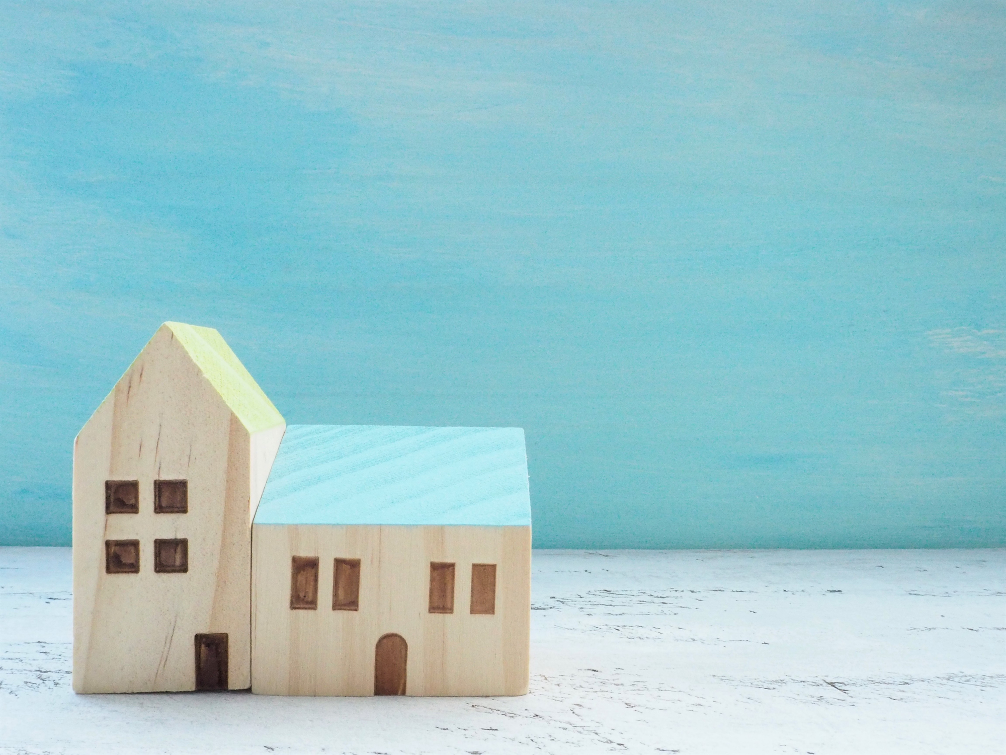 miniature house standing with wooden sky blue background