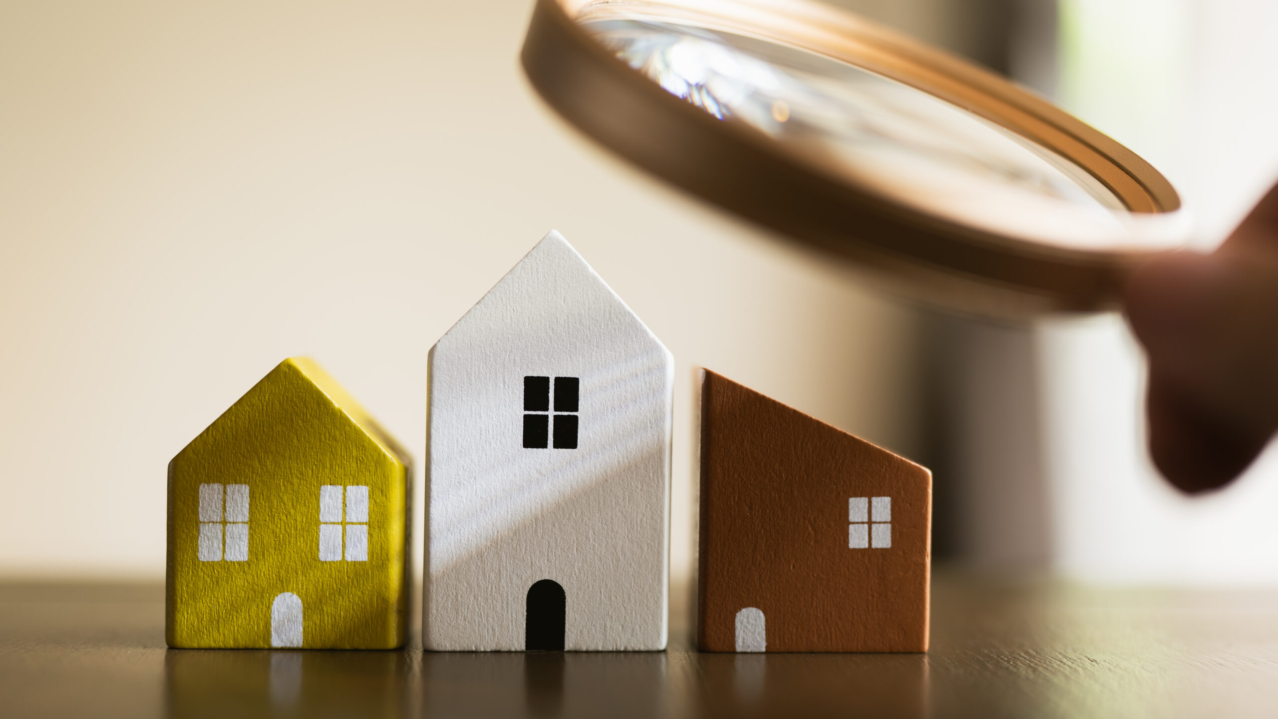 Hand holding magnifying glass and looking at house model, house selection, real estate concept. Hand holding magnifying glass and looking at house model, house selection, real estate concept.