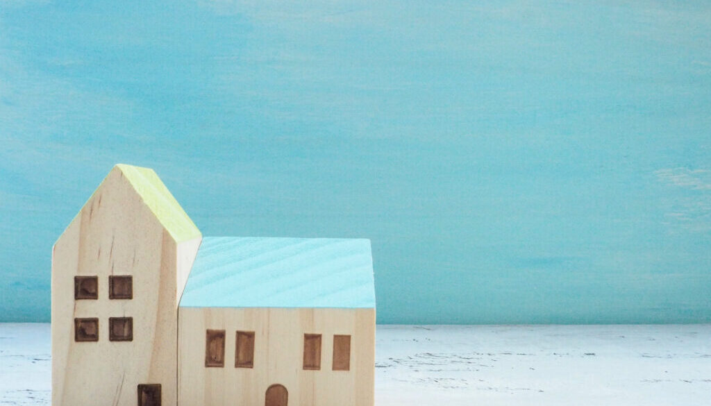 miniature house standing with wooden sky blue background